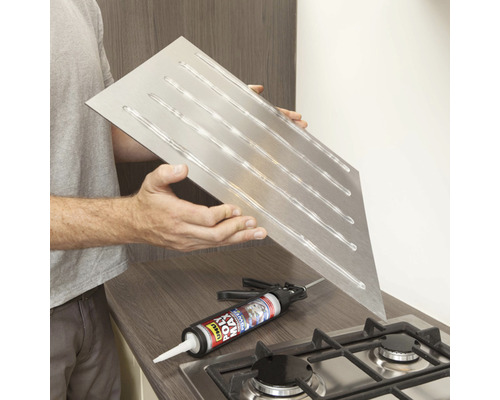 Edelstahl-Spritzschutz mit Klebstoffauftrag, dargestellt mit Klebstoffpistole auf einem Herd.