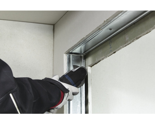 Un artisan coupe un profilé métallique avec un outil multifonction dans une construction sèche