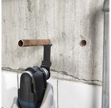 Outil multifonction coupant un tuyau de cuivre sur un mur