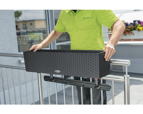 Personne monte un bac à fleurs de balcon noir avec support sur la balustrade