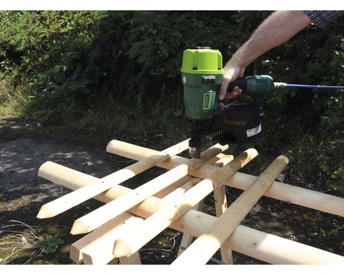 Eine Person verwendet einen Druckluftnagler, um eine Holzkonstruktion zu befestigen.