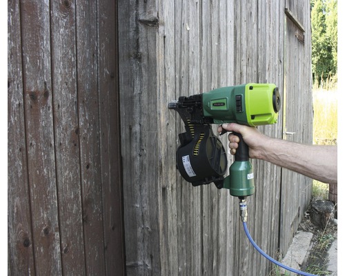 Eine Person benutzt einen Streifennagler an einer Holzwand.