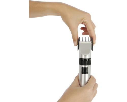 Une main fixe un embout sur une tondeuse à cheveux.