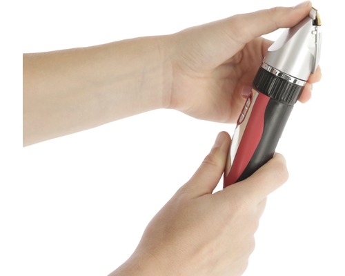 Une personne tient une tondeuse à cheveux dans sa main.