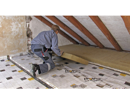Artisan posant des panneaux isolants sur un chantier avec des chevrons de toit