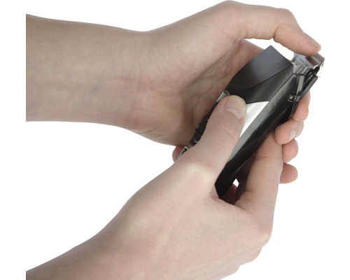 Les mains tiennent une tondeuse à cheveux