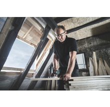 Artisan travaillant avec une défonceuse dans des combles.