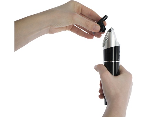 Les mains fixent un embout de tondeuse à poils de nez noir sur la tondeuse