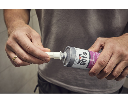 Un utilisateur fixe l''embout d''une cartouche de silicone sanitaire