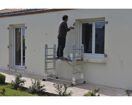 Mann streicht Hauswand mit einem Rollgerüst
