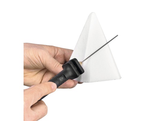 Person schneidet mit einem Styroporschneider einen Styroporkegel.