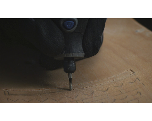 Une personne utilise un outil multifonction pour sculpter du bois.