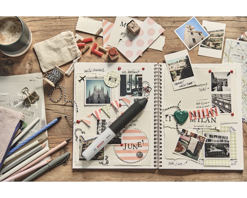 Dekorierte Seiten eines Fotoalbums mit Fotos und einem Bosch Klebestift auf einem Holztisch