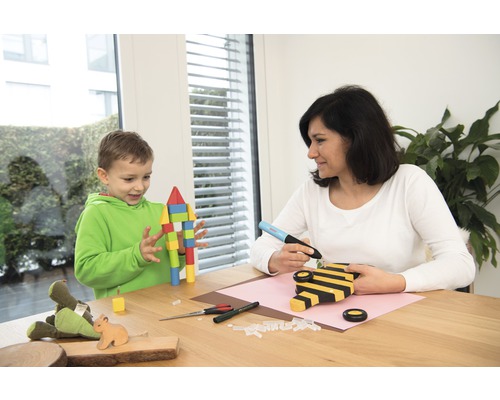 Une femme et un enfant bricolent avec un pistolet à colle chaude et du bois