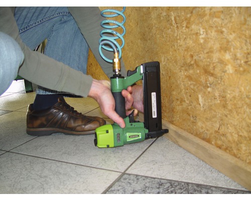 Eine Person verwendet einen Druckluftnagler für Holzarbeiten.