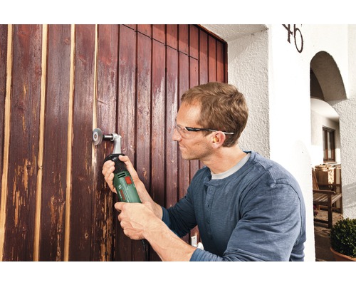 Mann arbeitet mit Multischleifer an einer Holztür.