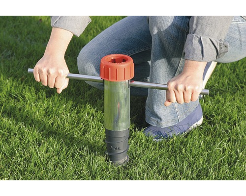 Personne utilisant un outil d''impact sur le sol dans l''herbe