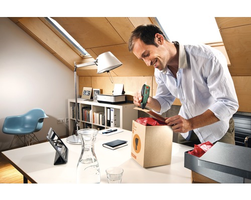 Un homme ferme un carton avec une agrafeuse à batterie dans un bureau.