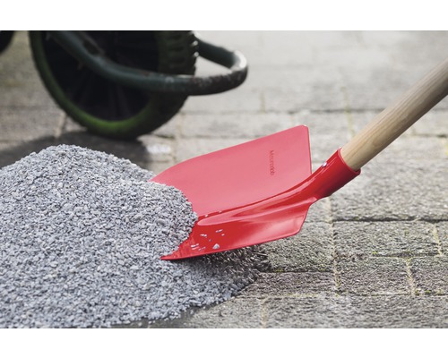 Rote Schaufel mit Holzgriff in einem Kieshaufen