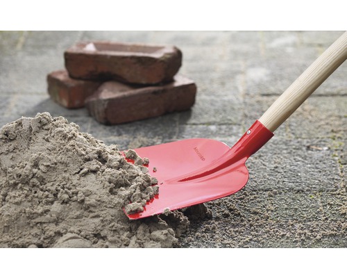 Spaten mit Sandhaufen und Ziegelsteinen