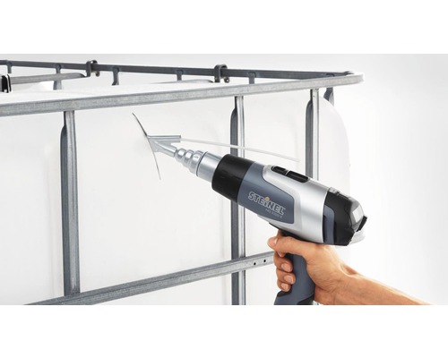 Une main tient un décapeur thermique Steinel sur la grille d''un conteneur IBC (Intermediate Bulk Container).