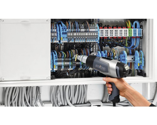 Électricien travaillant sur un tableau de distribution avec un pistolet thermique