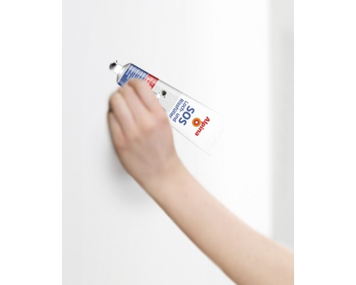 Eine Hand verwendet Alpina SOS Loch und Rissfüller Tube zum Ausbessern einer Wand