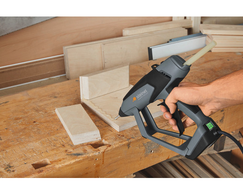 Handwerker klebt Holz mit einer Steinel Klebepistole auf einer Werkbank.