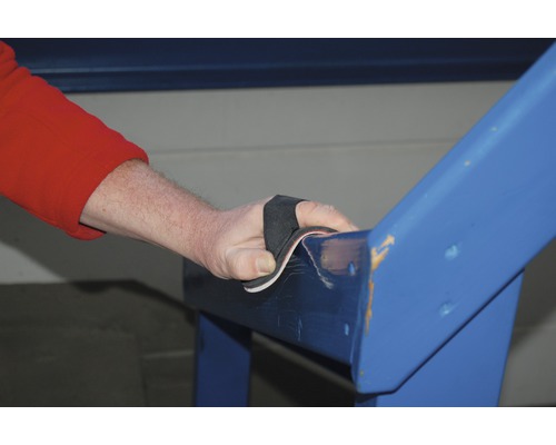 Eine Person schleift mit Schleifpapier ein blaues Holzgeländer ab.