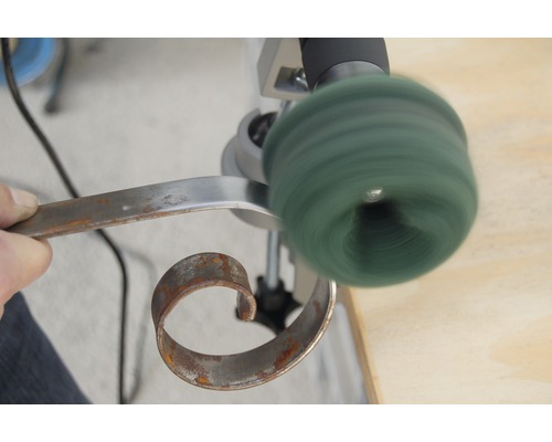 Eine Person poliert ein Metallstück mit einer Poliermaschine.