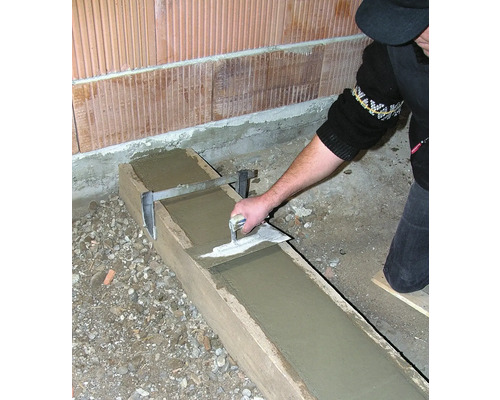 Une personne lisse du béton dans un coffrage en bois à l''aide d''une truelle.