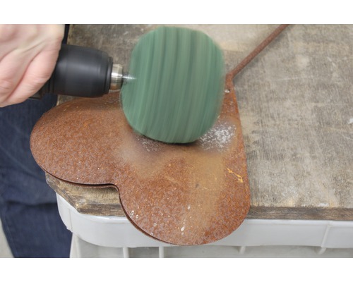 Elektrowerkzeug mit Schleifaufsatz an einem Werkstück aus Metall