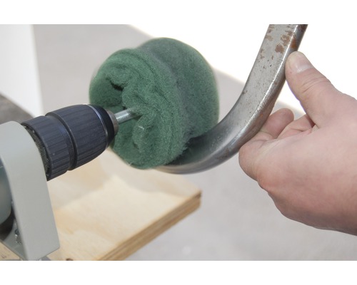 Bohrmaschine mit Polieraufsatz beim Polieren eines Metallstücks