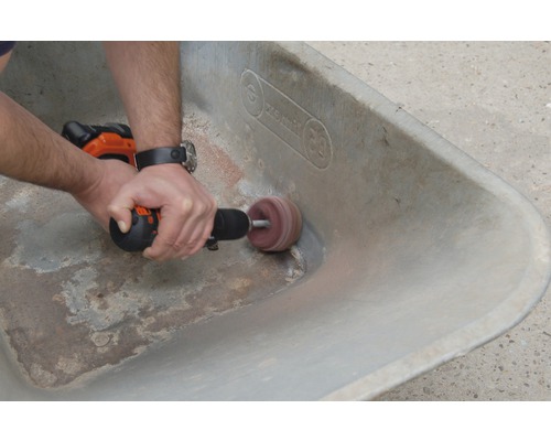 Eine Person schleift eine Schubkarre mit einer Schleifmaschine.