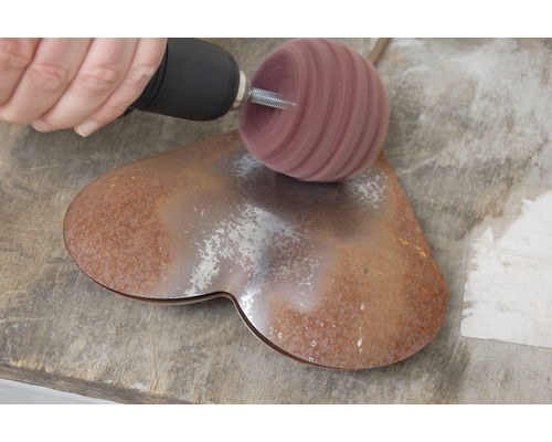 Elektrowerkzeug mit Schleifaufsatz bearbeitet ein metallisches Herz