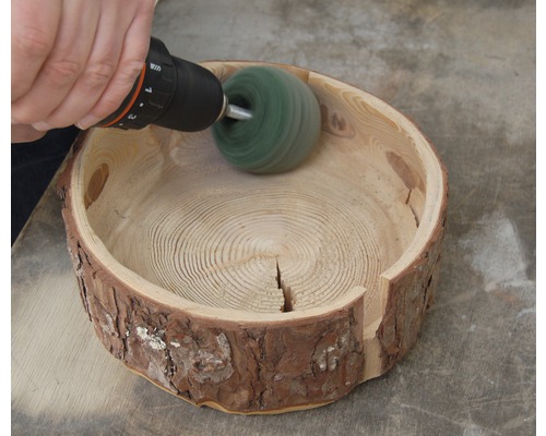 Holzschale wird mit einer Schleifscheibe und Bohrmaschine bearbeitet.