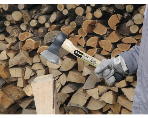 Spaltaxt mit Holzstamm und Holzstapel im Hintergrund