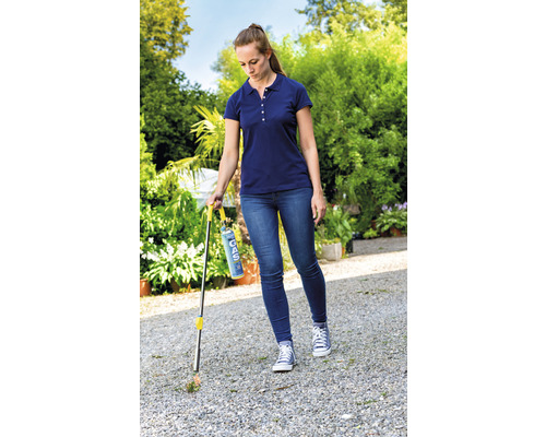 Eine Frau entfernt Unkraut mit einem Gasbrenner im Garten.