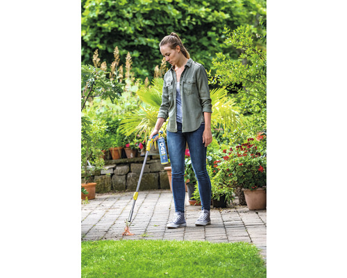 Frau benutzt einen Gasbrenner zur Unkrautvernichtung auf einer Terrasse.
