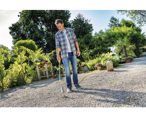 Ein Mann benutzt einen Gasbrenner zur Unkrautbekämpfung im Garten.