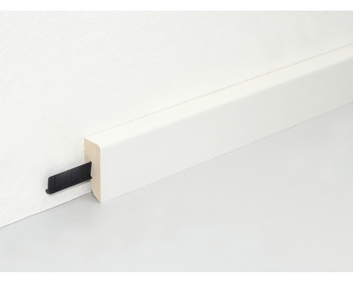 Weiss lackierte Holzfussleiste mit Befestigungsclip an Wand und Boden