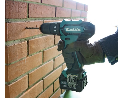 Perceuse-visseuse sans fil Makita perçant un mur de briques