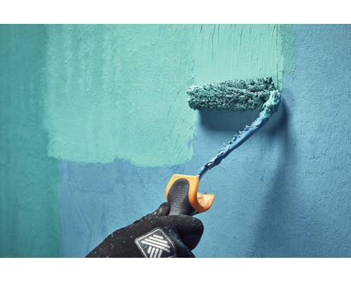 Une personne peint un mur avec un rouleau à peinture.