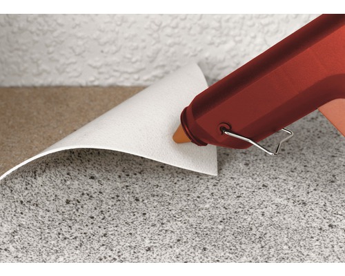 Heißklebepistole beim Anbringen von Wandverkleidung