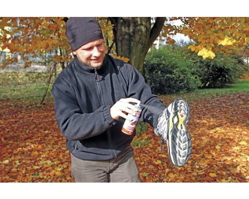 Un homme imperméabilise une chaussure avec un spray imperméabilisant à l''extérieur