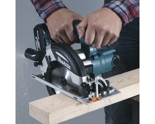 Une personne coupe une planche de bois avec une scie circulaire Makita.