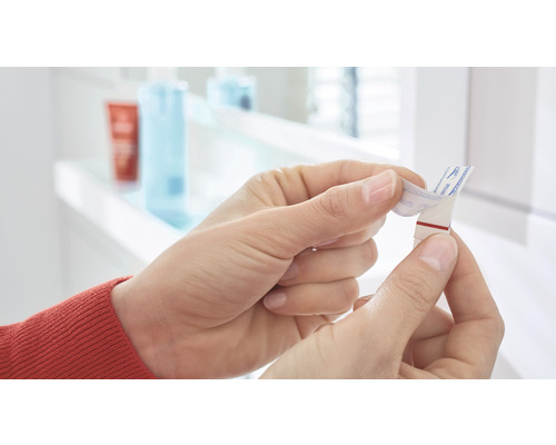 Eine Person entfernt die Schutzfolie von einem Klebestreifen.