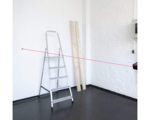 Pièce avec échelle, planches de bois et télémètre laser avec faisceau laser rouge