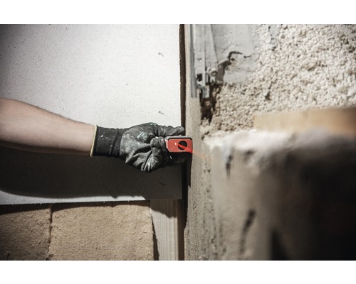 Une personne utilise un niveau laser sur un mur pour aligner un projet.