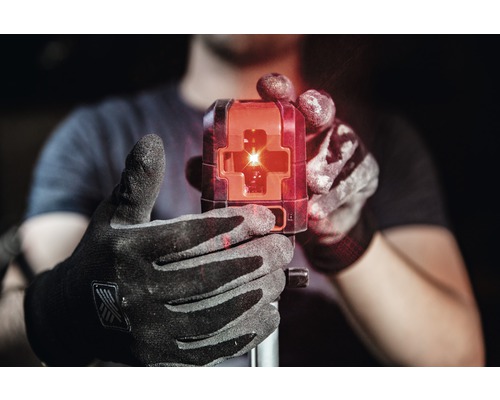 Eine Person hält einen Baulaser mit roten Laserstrahlen in der Hand.
